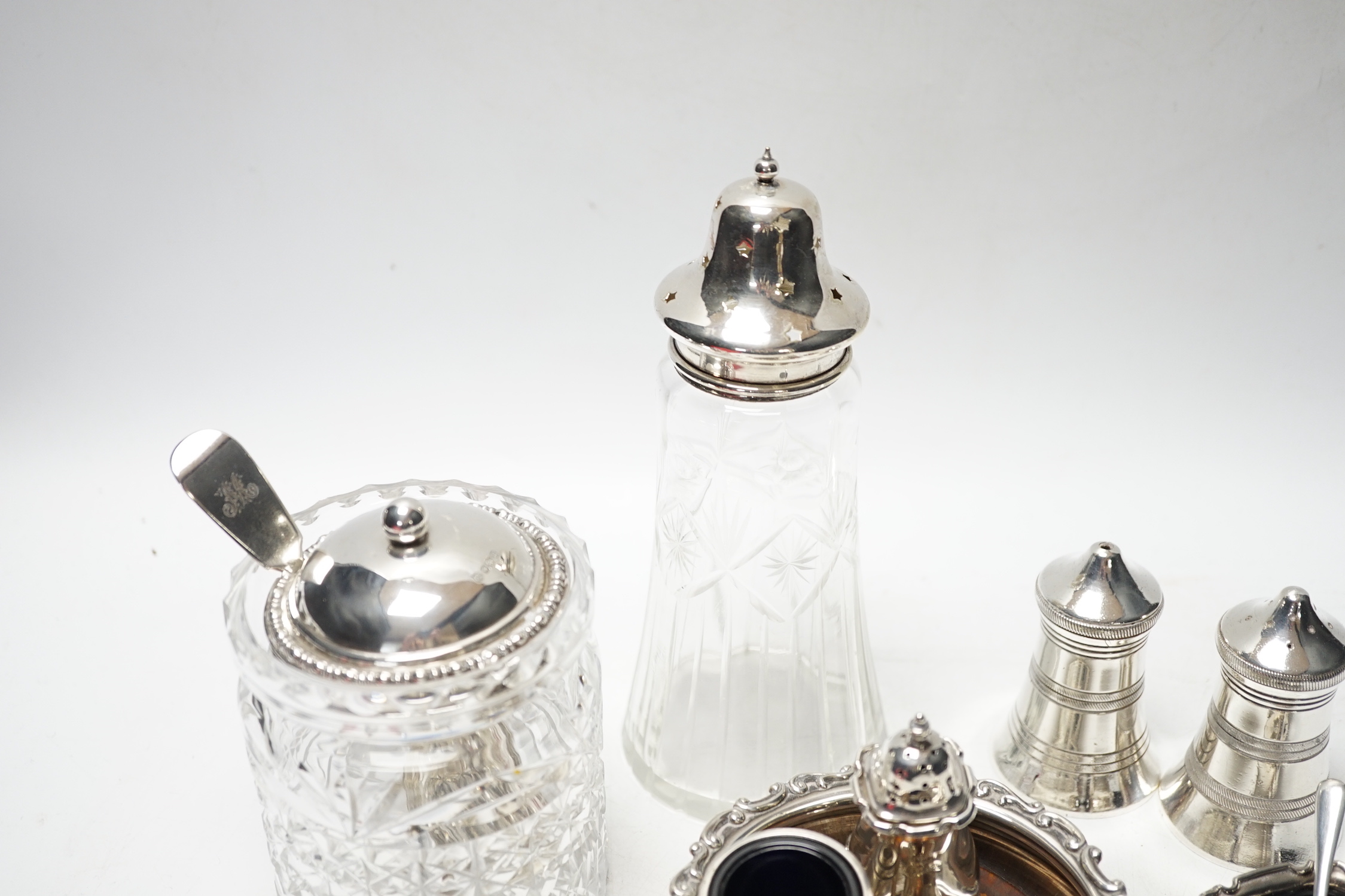 An Edwardian silver wine coaster, William Hutton & Sons, Birmingham, 1903, diameter 10.4cm, a later silver three piece condiment set, a silver mounted glass preserve jar, with a George silver teaspoon and six plated item